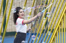 Молода жінка на ігровому майданчику робить бульбашки з бульбашковою паличкою — стокове фото