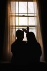 Silhouette of boy and girl, sitting in front of window, girl wearing bunny ears, rear view — Stock Photo