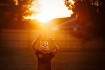 Мальчик практикующий американский футбол в саду — стоковое фото