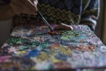 Крупный план мужчины, смешивающего масляные краски на палитре — стоковое фото