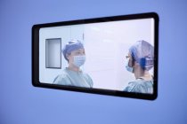 Fensterblick auf zwei Chirurginnen, die sich im Operationssaal der Geburtsstation unterhalten — Stockfoto
