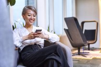 Бізнес-леді, використовуючи смартфон посміхаючись — стокове фото