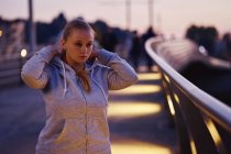 Kurvige junge Frau trainiert in der Abenddämmerung auf Fußgängerbrücke — Stockfoto