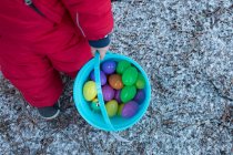 Cropped image of Boy holding bucket of toy eggs — Stock Photo