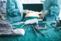 Nahaufnahme chirurgischer Instrumente mit Chirurgen, die im Operationssaal der Entbindungsstation operieren — Stockfoto