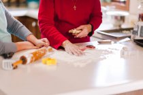 Girl and grandmother preparing flour on kitchen bench, mid section — Stock Photo