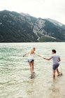 Casal em águas rasas de mãos dadas, Achensee, Innsbruck, Tirol, Áustria, Europa — Fotografia de Stock