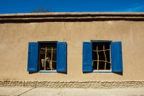 Duas janelas com persianas de madeira velhas na casa velha — Fotografia de Stock