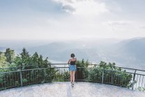 Vista trasera de la mujer joven en la plataforma de visualización con vistas al lago de Como, Lombardía, Italia - foto de stock
