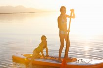 Two young girls paddle boarding on water — Stock Photo