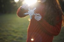Young woman holding Christmas star in rural setting — Stock Photo
