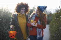 Friends carrying miniature pumpkins and bucket — Stock Photo