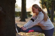 Kurvenreiche junge Frau trainiert und berührt Zehen im Park — Stockfoto