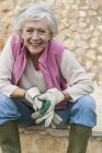 Retrato de una mujer mayor al aire libre, usando guantes de jardinería - foto de stock