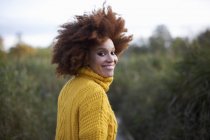 Portrait of woman with afro smiling over shoulder at camera — Stock Photo