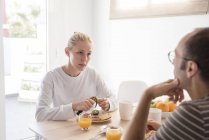 Mujer joven y novio hablando en la mesa del desayuno - foto de stock