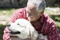 Старший мужчина обнимает собаку на улице — стоковое фото