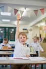 Школьник с поднятыми руками в классе начальной школы — стоковое фото