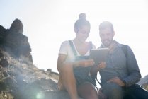 Young hiking couple looking at digital tablet in sunlit valley, Las Palmas, Canary Islands, Spain — Stock Photo