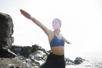 Jeune femme en posture de yoga guerrier sur la plage — Photo de stock