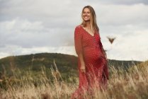 Портрет счастливой беременной женщины в красном платье на склоне горы — стоковое фото