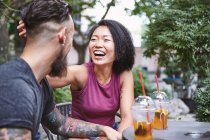 Multi ethnic hipster couple laughing at sidewalk cafe, Shanghai French Concession, Shanghai, China — Stock Photo