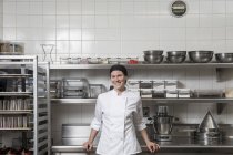 Портрет шеф-повара на коммерческой кухне, смотрящего на улыбающуюся камеру — стоковое фото
