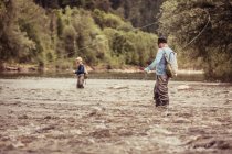 Двое мужчин ловят рыбу по щиколотку глубоко в реке - Мохье, Брезовица, Словенья — стоковое фото