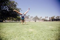 Estudante fazendo cartwheel no campo de esportes da escola — Fotografia de Stock