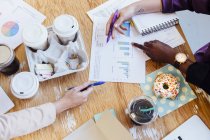 Zugeschnittene Ansicht der Hände von Geschäftsfrauen und Kaffeetassen auf dem Schreibtisch — Stockfoto