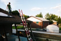 Trabalhador de pé no telhado da casa, a instalação de painéis solares — Fotografia de Stock