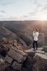 Mujer joven de pie sobre rocas y mirando a la vista, Sombrero Mexicano, Utah, EE.UU. - foto de stock