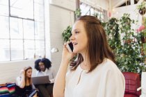 Side view of Woman in office making telephone call on smartphone — Stock Photo