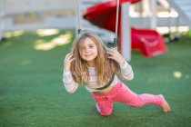 Girl at preschool, portrait lying on swing in garden — Stock Photo