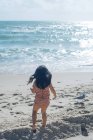Вид ззаду Маленька дівчинка стоїть на пляжі — стокове фото