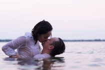 Целующаяся в воде одетая пара, Дестин, Флорида, США, Северная Америка — стоковое фото
