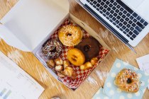Overhead view of doughnuts in cake box on desk — Stock Photo