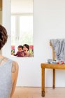 Mother and baby daughter looking in mirror, rear view — Stock Photo