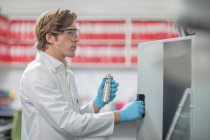 Чоловічий працівник на фабриці ниток, розміщення лабораторних зразків у хімічній печі — стокове фото