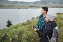 Pareja de pie junto a Dillon Reservoir, utilizando tableta digital, Silverthorne, Colorado, EE.UU. - foto de stock
