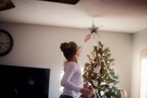Giovane ragazza mettendo su decorazioni natalizie — Foto stock