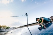 Workman installant des panneaux solaires sur le toit de la maison, vue à angle bas — Photo de stock