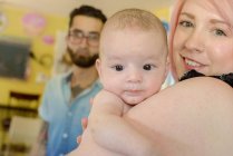 Woman with baby boy, husband in background — Stock Photo