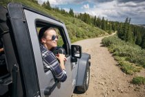 Young woman on road trip looking from car window in Rocky mountains, Breckenridge, Colorado, USA — Stock Photo