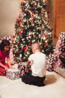 Brother and sister unwrapping gifts on Christmas day — Stock Photo
