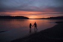 Силуэты пары на пляже на закате — стоковое фото