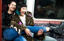 Две девушки смеются в подземном поезде — стоковое фото