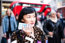 Jeune femme élégante dans la rue faisant appel à un téléphone intelligent, Londres, Royaume-Uni — Photo de stock
