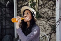 Молода жінка сидить на відкритому повітрі, п'є з пляшки — стокове фото