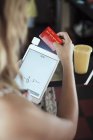 Vue sur l'épaule de la jeune femme tenant une tablette numérique et une carte de crédit — Photo de stock